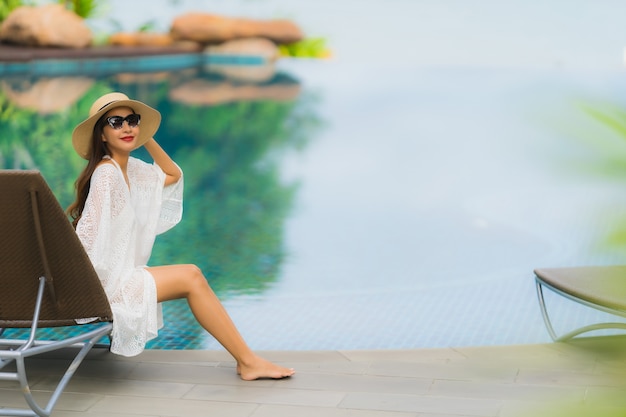 Retrato hermosa mujer asiática joven sonrisa feliz relajarse alrededor de la piscina en el hotel resort