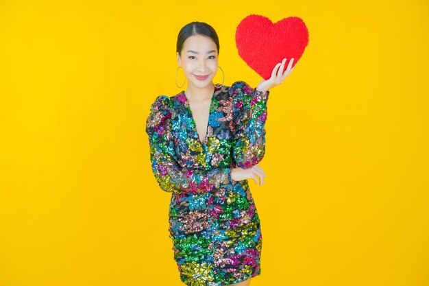 Retrato hermosa mujer asiática joven sonrisa con forma de almohada de corazón en amarillo