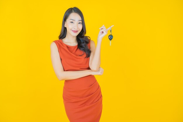 Retrato hermosa mujer asiática joven sonrisa con llave de coche en amarillo