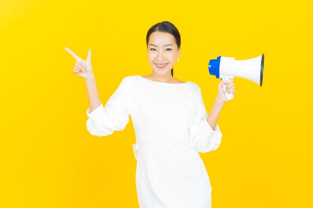 Retrato hermosa mujer asiática joven sonrisa con megáfono en amarillo