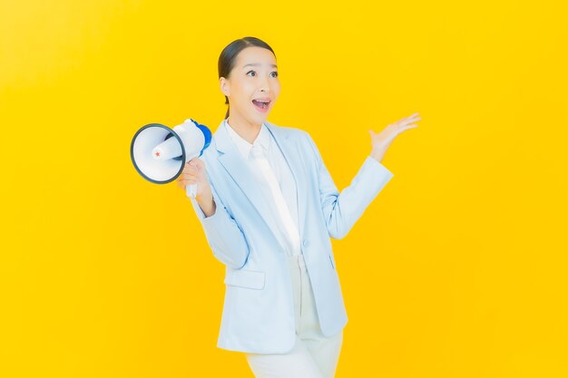 Retrato hermosa mujer asiática joven sonrisa con megáfono en amarillo