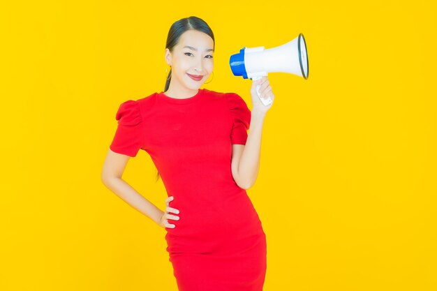 Retrato hermosa mujer asiática joven sonrisa con megáfono en amarillo