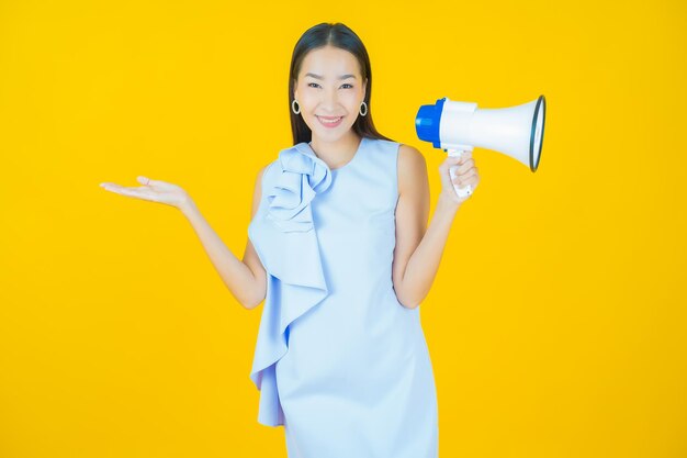 Retrato hermosa mujer asiática joven sonrisa con megáfono en amarillo