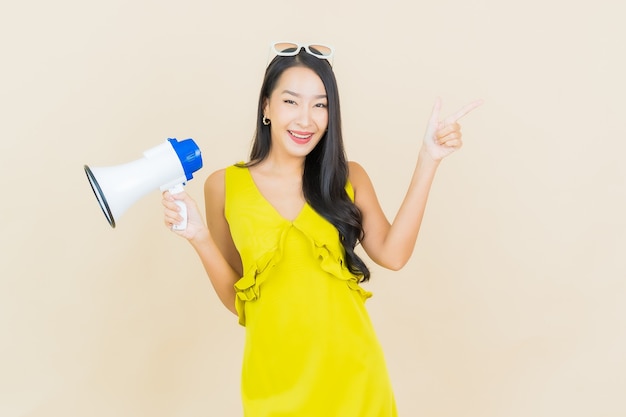 Retrato hermosa mujer asiática joven sonrisa con megáfono en la pared de color