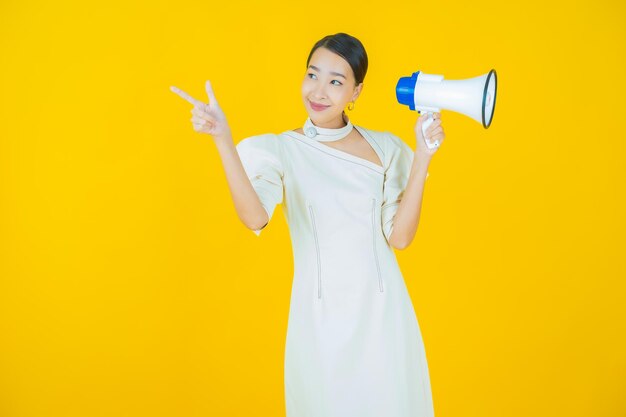 Retrato hermosa mujer asiática joven sonrisa con megáfono sobre fondo de color