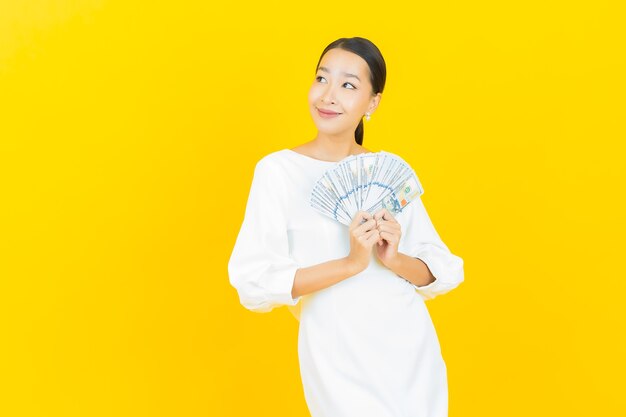 Retrato hermosa mujer asiática joven sonrisa con mucho dinero en efectivo y dinero en amarillo