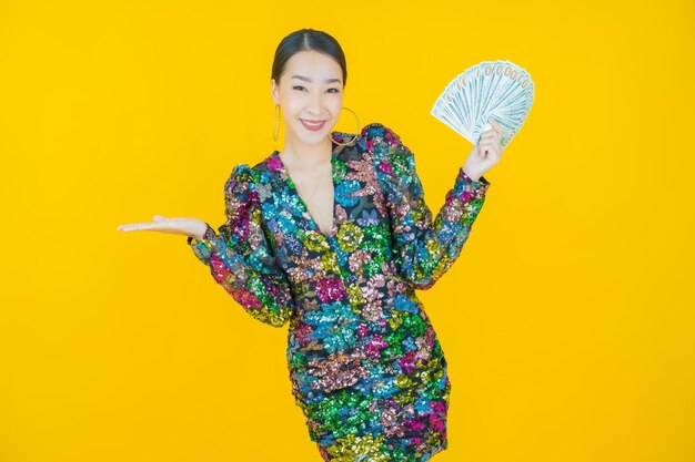 Retrato hermosa mujer asiática joven sonrisa con mucho dinero en efectivo y dinero en amarillo