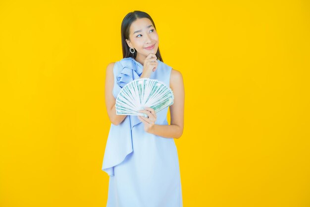 Retrato hermosa mujer asiática joven sonrisa con mucho dinero en efectivo y dinero en amarillo