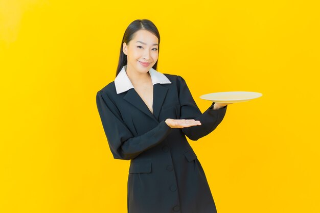 Retrato hermosa mujer asiática joven sonrisa con plato plato vacío en la pared de color