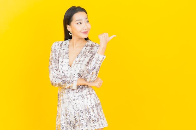 Retrato hermosa mujer asiática joven sonrisa posando en amarillo