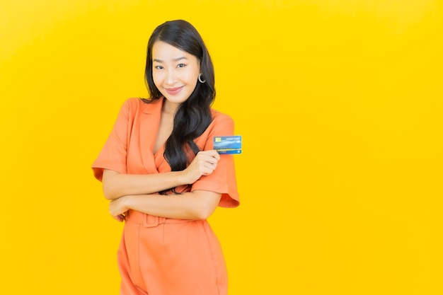 Retrato hermosa mujer asiática joven sonrisa con tarjeta de crédito en amarillo