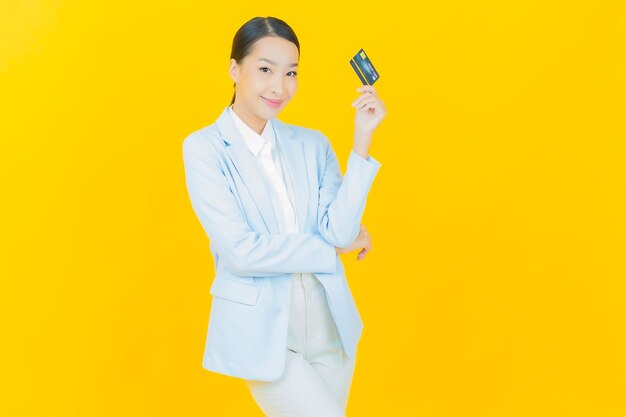 Retrato hermosa mujer asiática joven sonrisa con tarjeta de crédito en amarillo