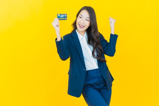 Retrato hermosa mujer asiática joven sonrisa con tarjeta de crédito en amarillo