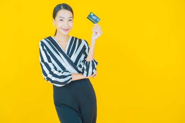 Retrato hermosa mujer asiática joven sonrisa con tarjeta de crédito en amarillo