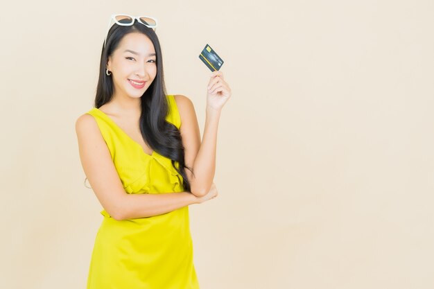 Retrato hermosa mujer asiática joven sonrisa con tarjeta de crédito en la pared de color