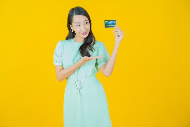 Retrato hermosa mujer asiática joven sonrisa con tarjeta de crédito sobre fondo de color