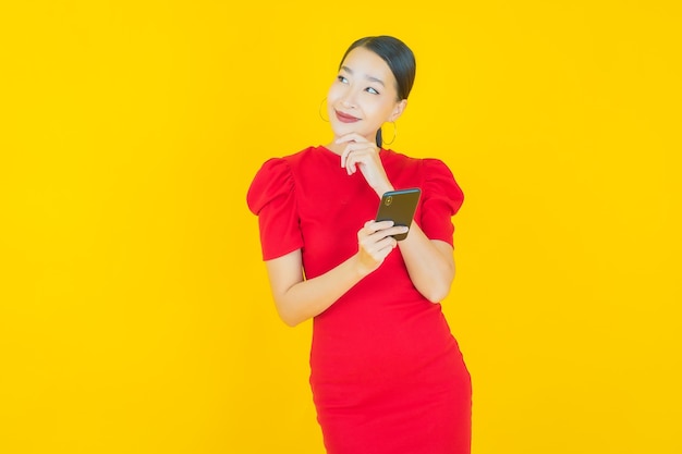 Retrato hermosa mujer asiática joven sonrisa con teléfono móvil inteligente en amarillo