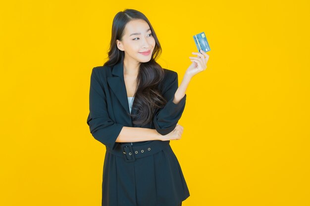 Retrato hermosa mujer asiática joven sonrisa con teléfono móvil inteligente en amarillo