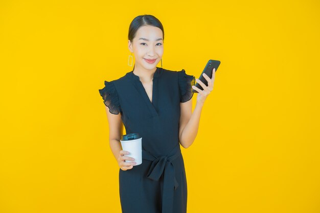 Retrato hermosa mujer asiática joven sonrisa con teléfono móvil inteligente en amarillo