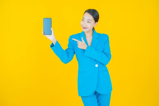 Retrato hermosa mujer asiática joven sonrisa con teléfono móvil inteligente en amarillo