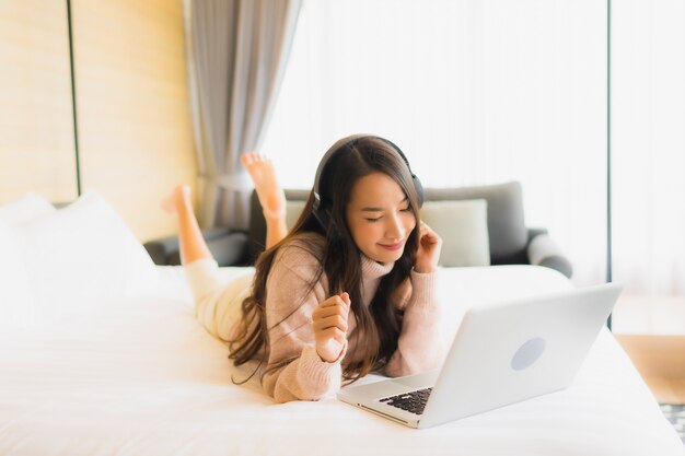 Retrato hermosa mujer asiática joven usando laptop con auriculares para escuchar música