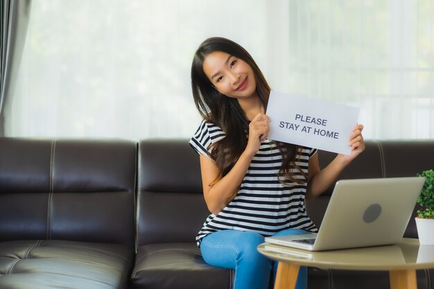 Retrato hermosa mujer asiática joven usando laptop o computadora noterbook en el sofá con trabajo conceptual desde casa