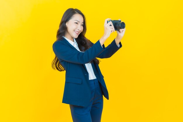 Retrato hermosa mujer asiática joven usar cámara en amarillo