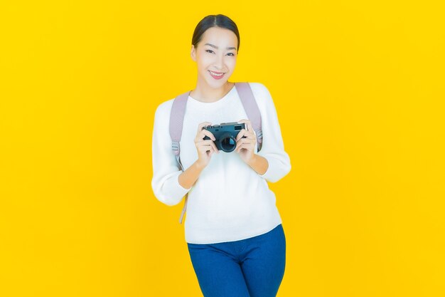 Retrato hermosa mujer asiática joven usar cámara en amarillo