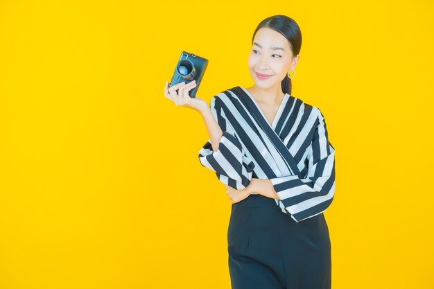 Retrato hermosa mujer asiática joven usar cámara en amarillo