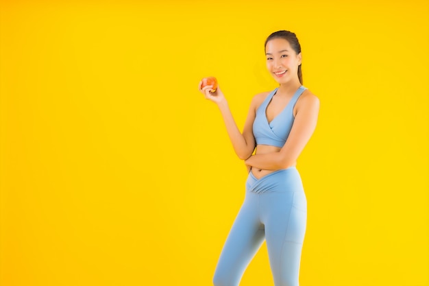 Retrato hermosa mujer asiática joven usar ropa deportiva lista para hacer ejercicio en amarillo