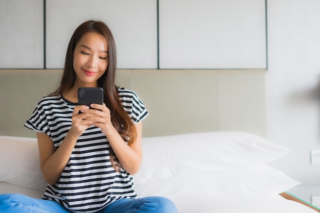 Retrato hermosa mujer asiática joven usar teléfono móvil inteligente en dormitorio