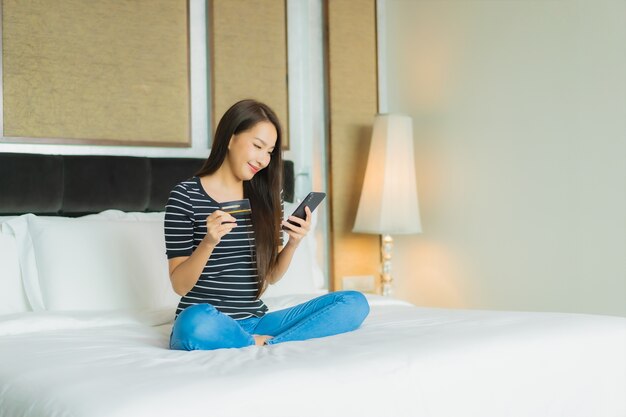 Retrato hermosa mujer asiática joven utiliza teléfono móvil inteligente con computadora portátil y tarjeta de crédito para compras en línea