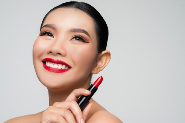 Retrato de hermosa mujer asiática con lápiz labial en la mano