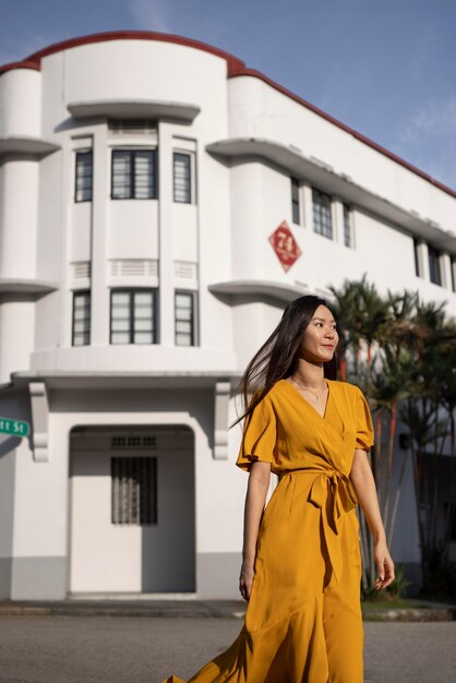 Retrato de hermosa mujer asiática posando en la ciudad con vestido amarillo