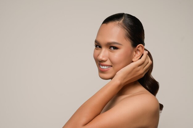 Retrato de hermosa mujer asiática toca la oreja y sonríe