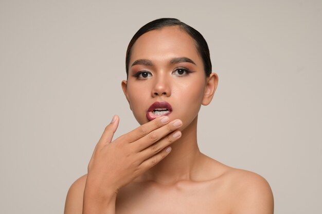 Retrato de hermosa mujer asiática con toques de dedos en los labios, maquillaje de naturaleza hermosa piel limpia natural