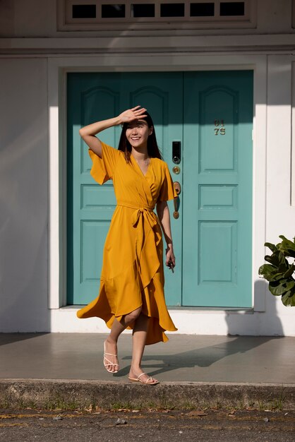 Retrato de hermosa mujer asiática en vestido amarillo posando al aire libre en la ciudad