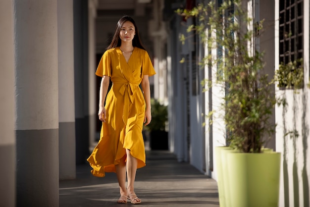 Retrato de hermosa mujer asiática en vestido amarillo posando al aire libre en la ciudad