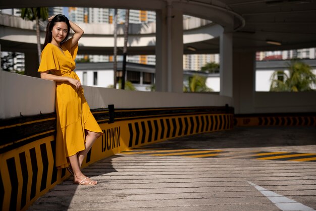 Retrato de hermosa mujer asiática en vestido amarillo posando al aire libre en la ciudad