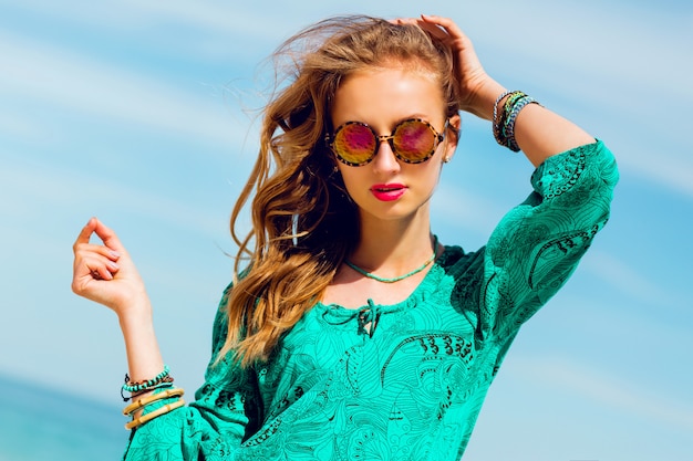 Retrato de hermosa mujer bronceada delgada con perfecto bode en brillante vestido de playa boho y accesorios geniales