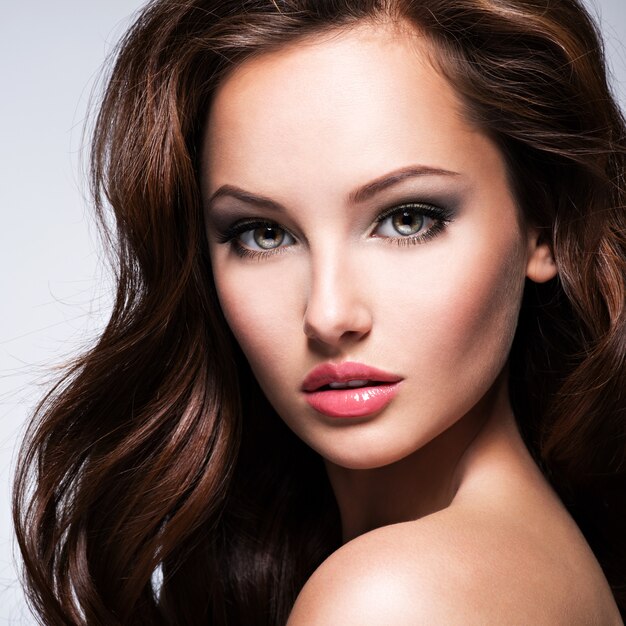 Retrato de la hermosa mujer con cabello castaño rizado posando sobre fondo oscuro