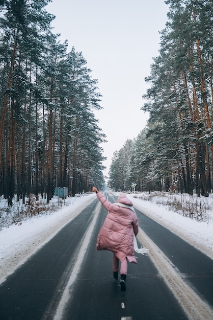 Retrato de una hermosa mujer caucásica en una carretera a través del bosque nevado