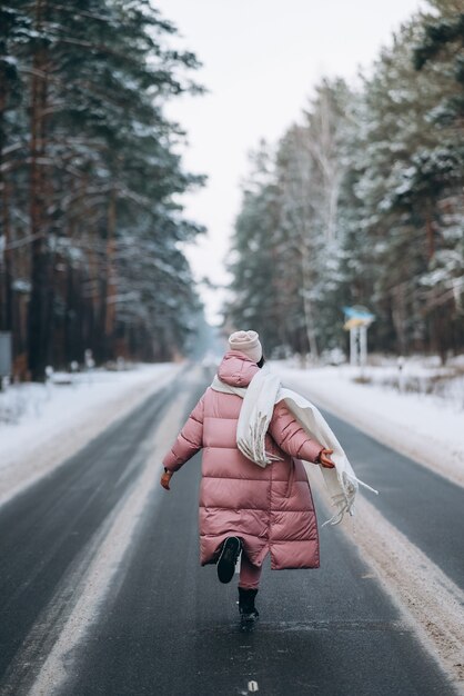 Retrato de una hermosa mujer caucásica en una carretera a través del bosque nevado