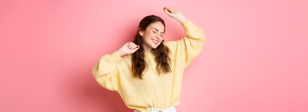 Foto gratuita retrato de una hermosa mujer caucásica divirtiéndose bailando y disfrutando de la fiesta levantando las manos en rela