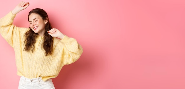 Foto gratuita retrato de una hermosa mujer caucásica divirtiéndose bailando y disfrutando de la fiesta levantando las manos en rela