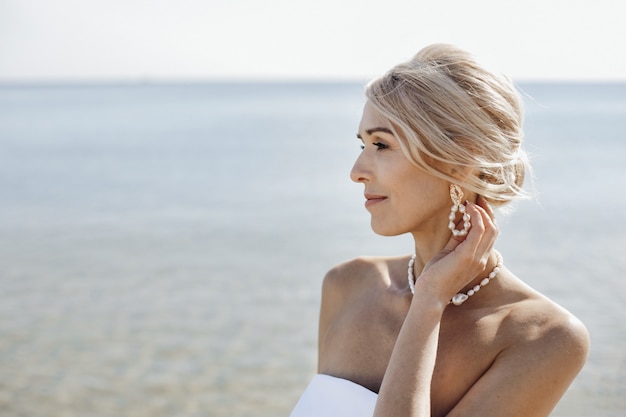 Retrato de hermosa mujer caucásica rubia en el día soleado cerca del mar