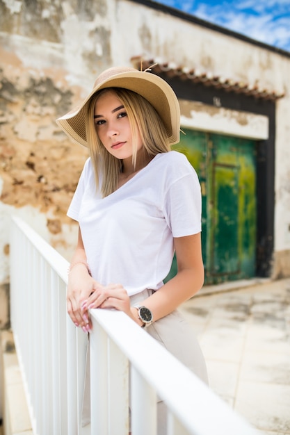 Retrato de una hermosa mujer caucásica en la terraza de verano con una sonrisa en el sombrero de verano