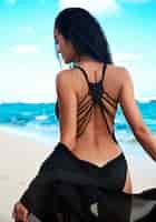 Foto gratuita retrato de hermosa mujer caucásica tomar el sol modelo con cabello largo y oscuro en traje de baño negro con capa de vuelo posando en la playa de verano con arena blanca en el cielo azul y el océano