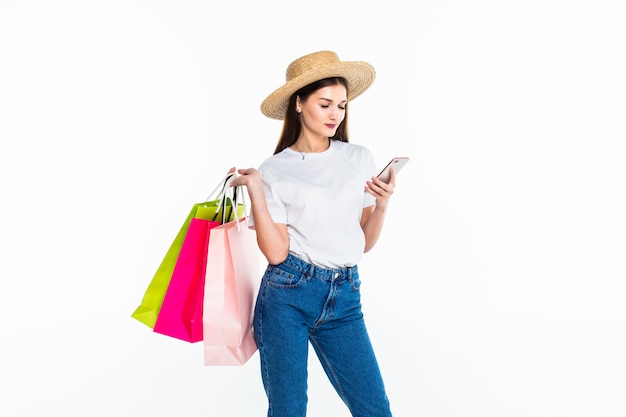 Retrato de hermosa mujer de compras usando su teléfono inteligente aislado en la pared blanca