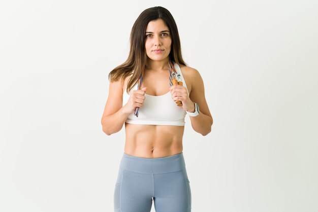 Retrato de una hermosa mujer deportiva que termina un entrenamiento fuerte. Atleta femenina lista para comenzar a saltar la cuerda para su entrenamiento cardiovascular diario